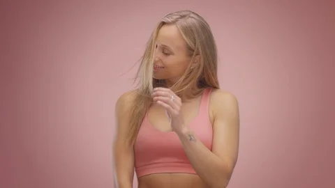 Blond model in studio on pink background with hair blowing in air Stock Footage 107516381