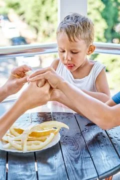 Blond preschooler boy eats slice of fresh melon among brothers Stock Photos