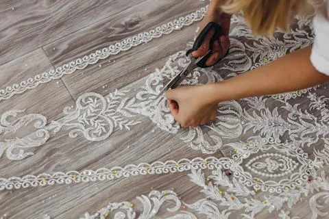 The blond professional tailor is correcting her white ornament for wedding .. Stock Photos