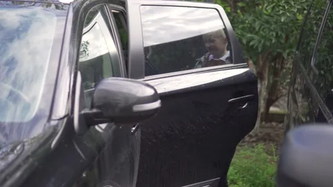 A blond schoolboy gets into the car in the back seat Stock Footage 224718108