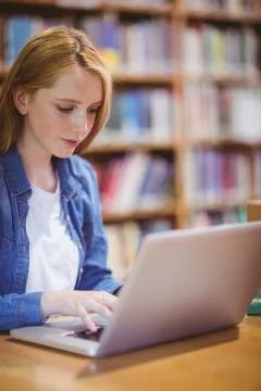 Blond student using laptop in library 스톡 사진