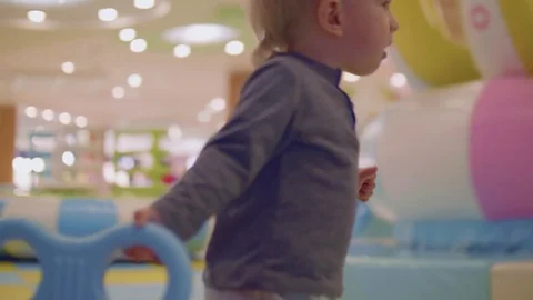 Blond toddler pulls toy car chewing orange Stock Footage 84658482