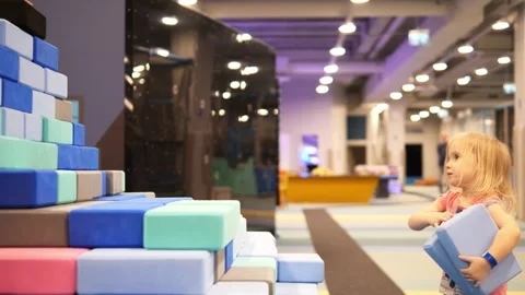 Blond toddler stacking soft blocks, constructing colorful wall during playful Vidéo 303820667