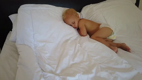  a blond two-year-old child sleeps on a white sheet. Stock Footage 107404655