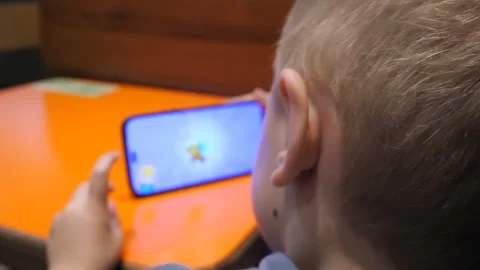 A blond white boy of 3-5 years old with a phone. View from behind, the child Stock Footage 313323677