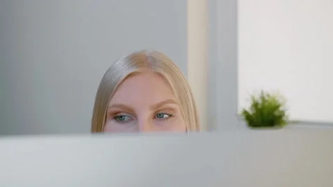 Blond woman attentively looking at computer monitor in modern office Stock Footage 340136732
