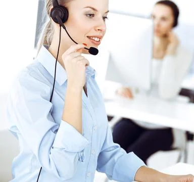 Blond woman call operator is using computer and headset for consulting clients Stock Photos