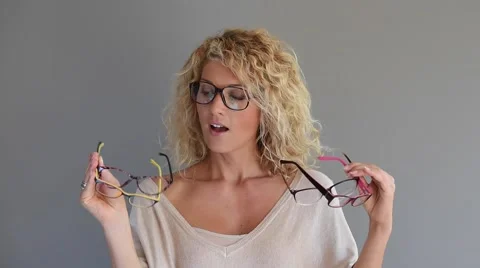 Blond woman with curly hair choosing between different eyeglasses Stock Footage