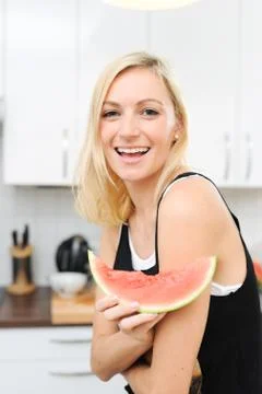 Blond woman eats melon Stock Photos