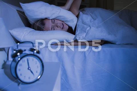 Blond woman putting pillows on her ears Stock Photos