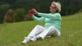 Blond woman sitting in the meadow on green grass and making photos HD Footage