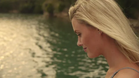 Blond woman's face as she sits beside water. Stock Footage 43637776