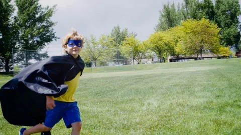 Blonde 4 year old boy pretending to be super hero playfully runs from camera 스톡 동영상 127547459