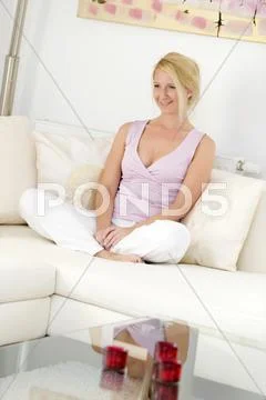 Blonde, attractive woman, 35, sitting comfortably on a sofa Stock Photos
