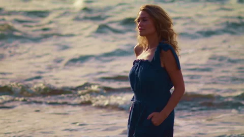 Blonde on the background of the waves in the sunbeams of the sunset. Video stock 225119222