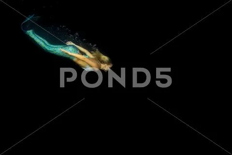 Blonde beautiful Siren Mermaid while diving underwater in the deep blue sea Stock Photos