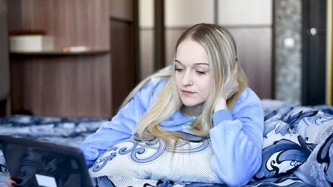 Blonde in bed resting , working in a laptop, eating dessert in daylight Stock Footage 106697205