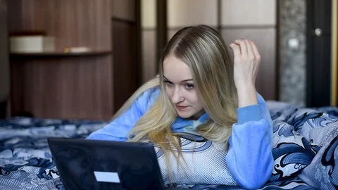 Blonde in bed resting , working in a laptop, eating dessert in daylight Video stock 106697267