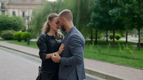 A blonde in a black jacket and a man with a beard are hugging against a Stock Footage 170500631