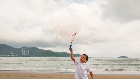 Blonde boy blowing soap bubbles at seaside. Stock Footage 261943721