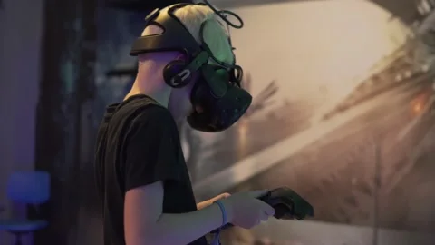 The blonde boy plays the game in virtual reality glasses in the club augmented Stock Footage 142569515