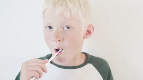 The blonde boy is quick to brush his teeth with a toothbrush on a white Stock Footage 134668045