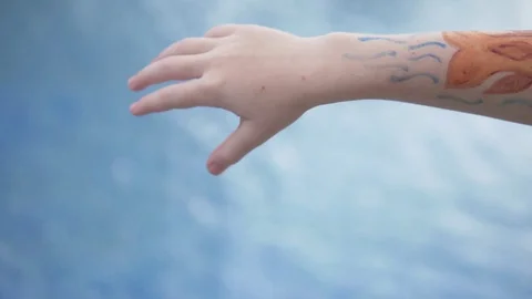 The blonde boy shows aqua makeup in the form of a fish on his arm Stock Footage 122308771