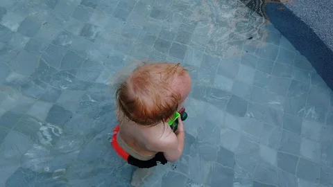 Blonde boy of two years playing with a toy, sitting in the pool. Stock Footage 104698614