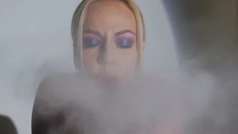 Blonde with bright makeup blows flour into camera and smiles.Slow motion Stock Footage 199256358