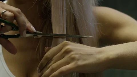 The blonde cuts off her curl with scissors 스톡 동영상 113448726