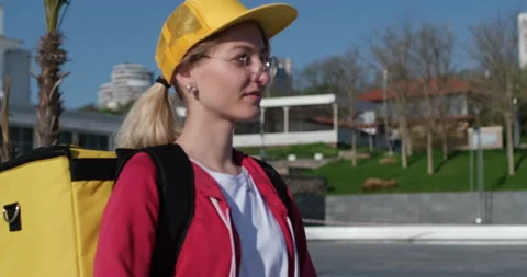 Blonde delivery worker with branded backpack and yellow cap Stockbeeldmateriaal 155795070