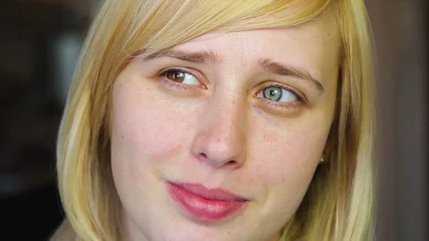 Blonde with different eyes looks at the camera and smiles 動画素材 73990301