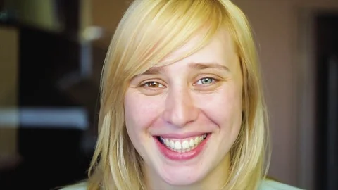 Blonde with different eyes looks at the camera and smiles 動画素材 73990307