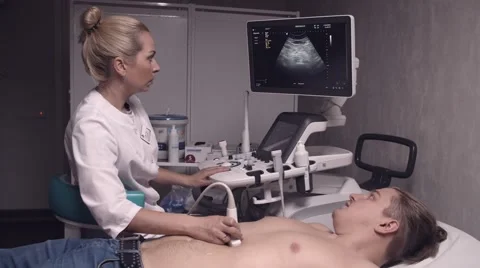 Blonde doctor talking to a patient while doing ultrasonography Stock Footage 62348076