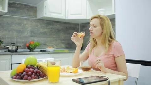 Blonde drinking tea with croissant at home in his kitchen Stock Footage 70286627