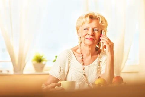 Blonde eldery woman using cell phone, at home Stock Photos