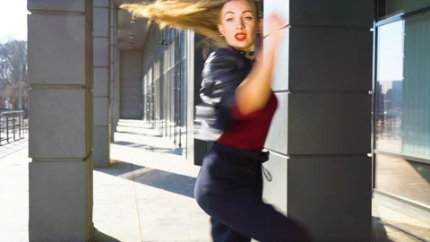 Blonde female dancer looking in the camera and dancing in city landscape Stock Footage 105871902
