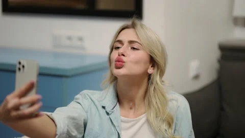 Blonde female posing at the smartphone camera at home Stock Footage 234663039