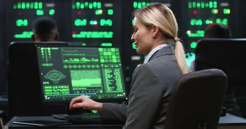 Blonde female programmer sitting at computer in server room working with Stock Footage 148403923