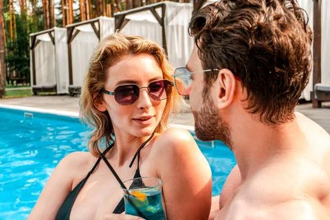 Blonde female spending time with her companion by an outdoor swimming pool over Stock Photos