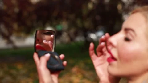 Blonde girl preening while looking in the mirror in the park Stock Footage 292959445