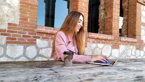 Blonde girl sitting at a table working with her laptop  Stock Footage 129147991