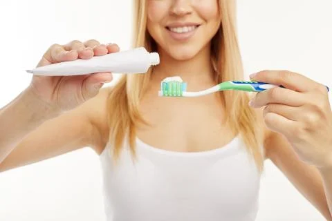 Blonde girl smiles while using toothpaste and toothbrush. Stock Photos