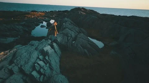 Blonde girl walking on rocks by ocean Stock Footage