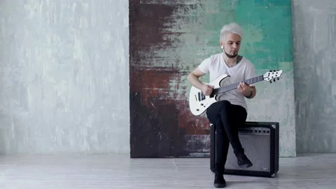 Blonde guy sitting and playing the guitar Stock Footage 103997411