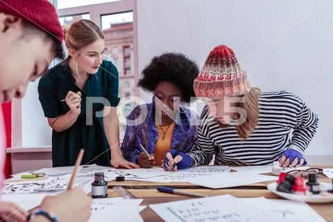 Blonde-haired group leader helping her trainees with painting Stock Photos
