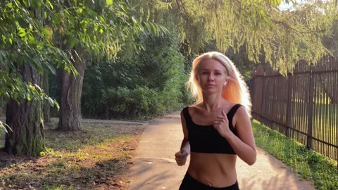 BLONDE JOGGING in the rays of a summer sunset. Romantic summer park, jogging Stock Footage 207559113