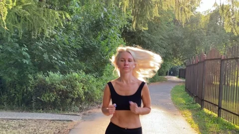 BLONDE JOGGING in the rays of a summer sunset. Romantic summer park, jogging Stock Footage 207559555