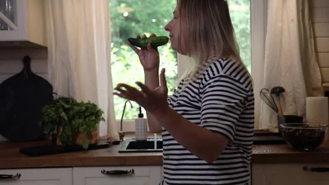 Blonde in the kitchen washing vegetables, having fun and singing Stock Footage 277113791