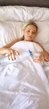 Blonde lying in bed drinking water in the morning 写真素材